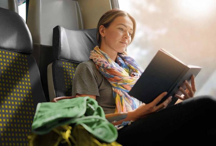 Kép az utazási ajánlatok menüpontcsoport illusztrálására. A képen egy GYSEV vonaton utazó nő olvas.