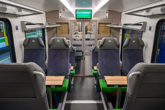 Az első GYSEV FLIRT InterCity motorvonat másodosztályú utastere kényelmes ülésekkel és asztalokkal.