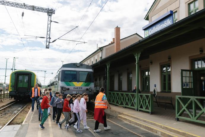 Gyerekcsoport érkezik a celldömölki vasútállomás peronjára egy GYSEV mozdony mellett.